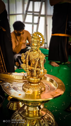 Golden brass statue of Hindu deity Ganesha seated on ornate pedestal during temple ceremony HD phone wallpaper