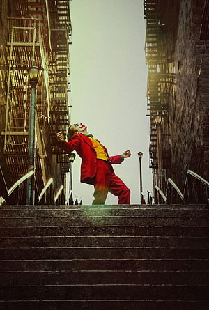 Joker dancing on the iconic Gotham City staircase in a red suit HD phone wallpaper