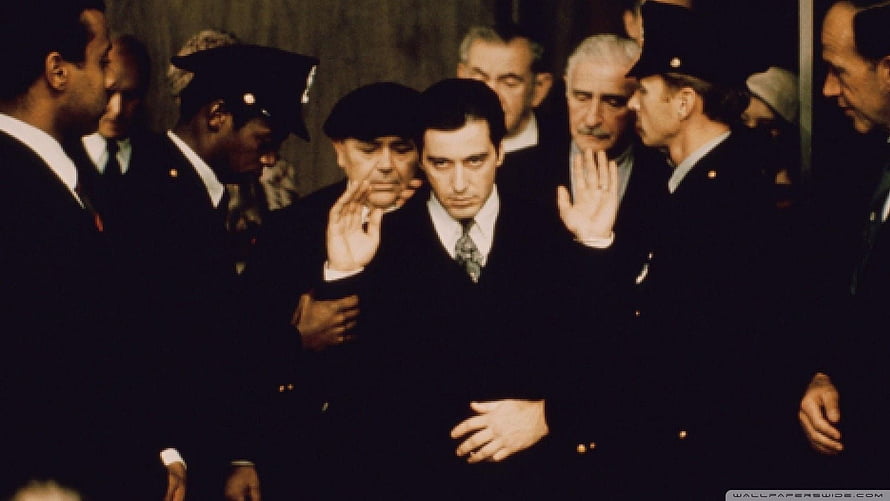Michael Corleone flanked by officers in a tense courtroom scene from The Godfather HD wallpaper