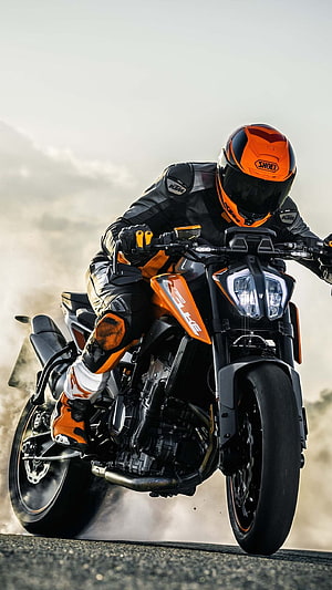 KTM Duke motorcycle rider in full gear performing a wheelie on asphalt road HD phone wallpaper