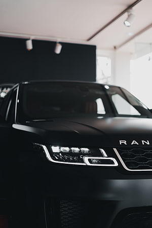 Matte Black Range Rover Front Fascia with LED Headlights in a Modern Showroom Setting HD phone wallpaper
