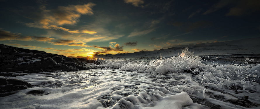 Dramatic Ocean Sunset with Crashing Waves and Rocky Coastline HD wallpaper