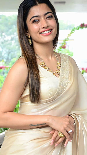 Rashmika Mandanna in an elegant cream silk saree with gold jewelry and a warm smile HD phone wallpaper
