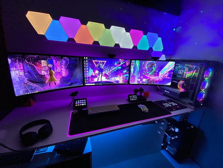 Triple Monitor Gaming Setup with RGB Hexagon Lights and Neon Purple Ambiance HD wallpaper