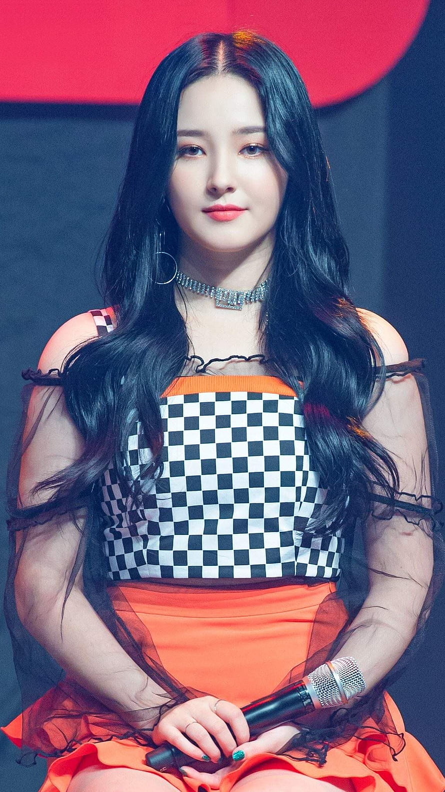 Nancy from Momoland in a stylish black and white checkered top with orange skirt holding a microphone HD phone wallpaper