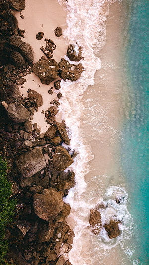 Aerial View of Turquoise Waves Crashing on Rocky Sandy Beach HD phone wallpaper