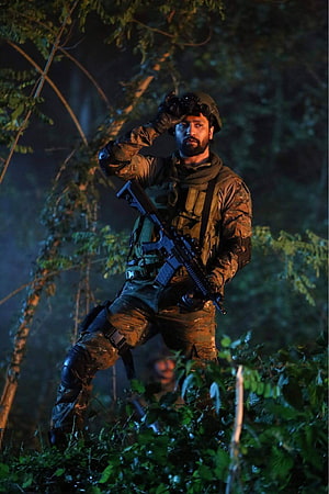 Soldier in camouflage gear holding rifle and binoculars in dark forest at night HD phone wallpaper
