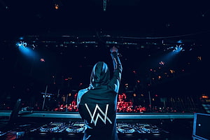 Alan Walker performing at a concert with raised arm and DJ equipment on stage HD wallpaper