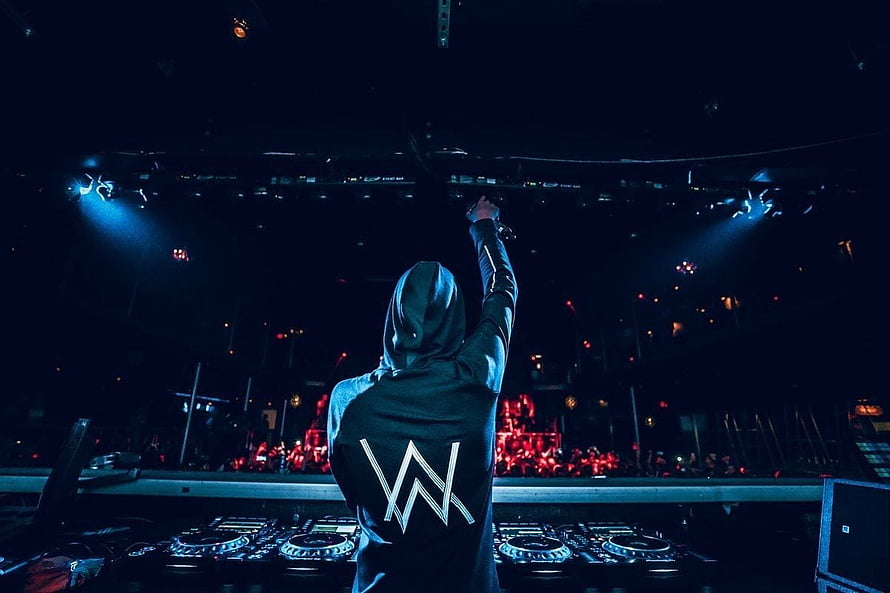 Alan Walker performing at a concert with raised arm and DJ equipment on stage HD wallpaper