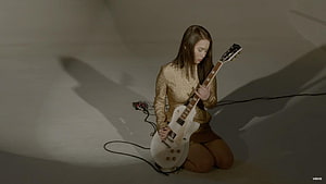 Mitski Playing White Electric Guitar in Gold Sequined Outfit HD wallpaper