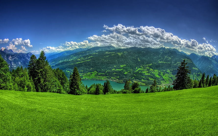 Vibrant Green Pastures and Alpine Lake Under a Dramatic Summer Sky HD wallpaper