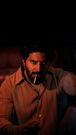 Dulquer Salmaan in moody low-light portrait with cigarette and intense gaze HD phone wallpaper