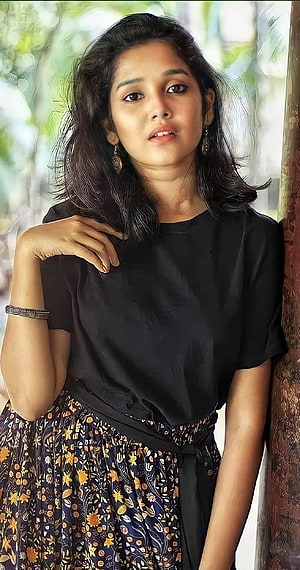 Anikha Surendran in Black Top and Floral Skirt Leaning Against Tree HD phone wallpaper