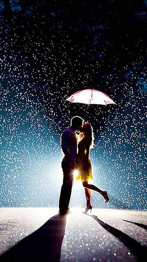 Silhouetted Couple Sharing a Kiss Under a Pink Umbrella in the Rain at Night HD phone wallpaper