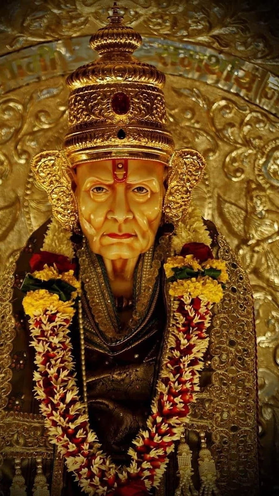 Golden Statue of Sai Baba Adorned with Flower Garlands and Ornate Crown HD phone wallpaper