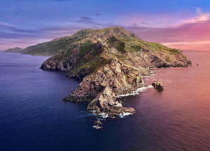Aerial View of Rugged Coastal Island at Sunset with Pink and Purple Sky HD wallpaper
