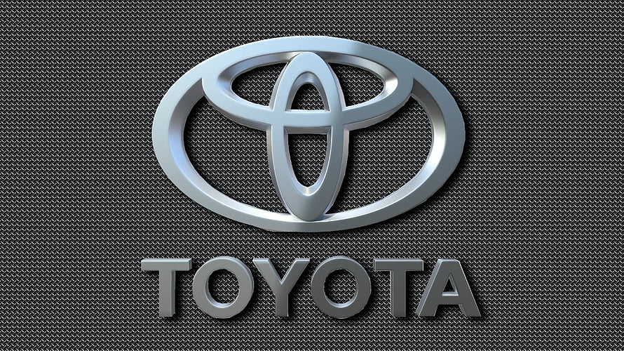 Sleek Silver Toyota Emblem on Dark Textured Carbon Fiber Background HD wallpaper
