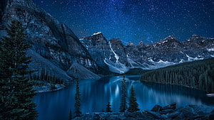 Starry Night Over Mountain Lake with Pine Trees and Snow-Capped Peaks HD wallpaper