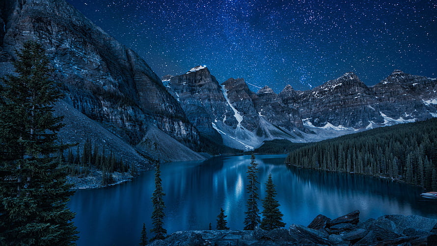 Starry Night Over Mountain Lake with Pine Trees and Snow-Capped Peaks HD wallpaper