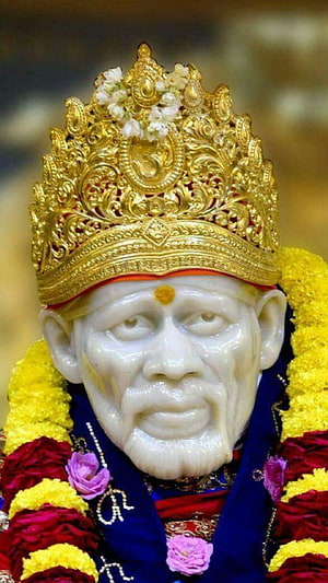 Sacred Statue of Sai Baba Adorned with Golden Crown and Flower Garlands HD phone wallpaper