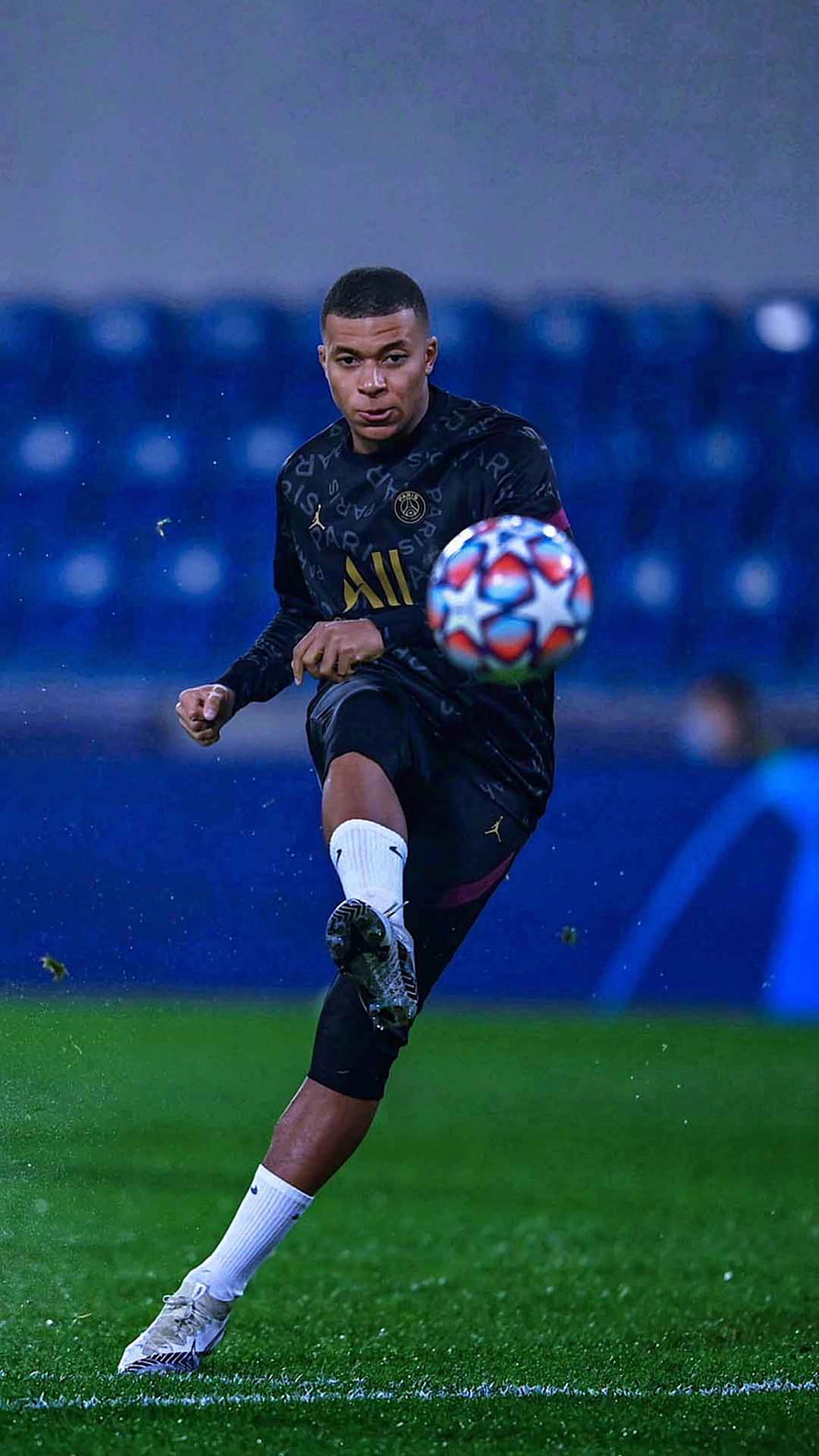 Kylian Mbappe in PSG kit striking a Champions League ball on a rainy night pitch HD phone wallpaper