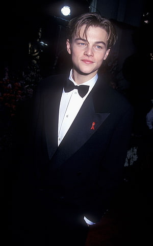 Young Leonardo DiCaprio in a Classic Black Tuxedo with Red Ribbon Pin at a Formal Event HD phone wallpaper