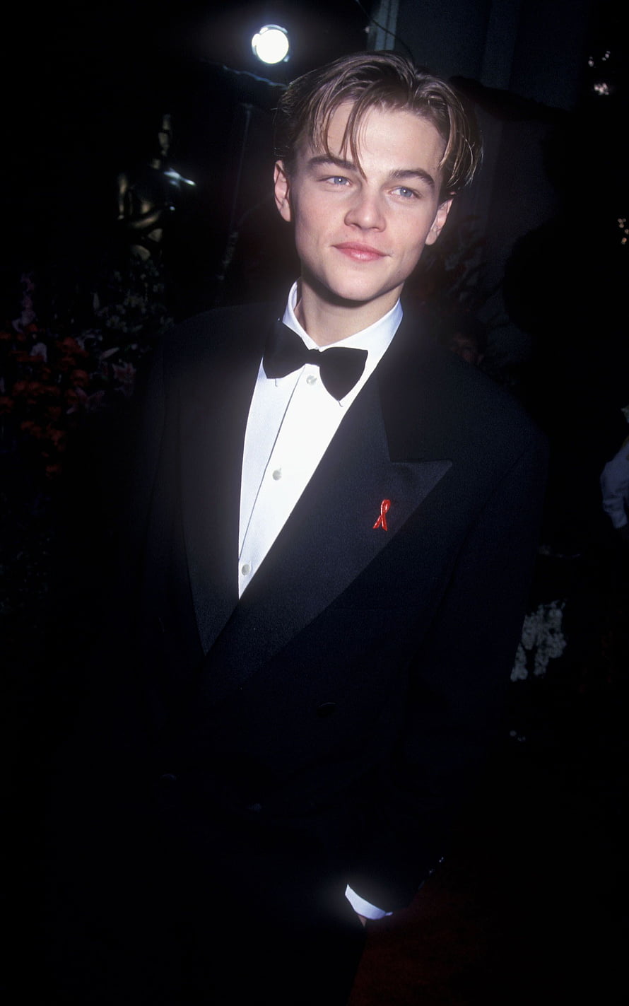 Young Leonardo DiCaprio in a Classic Black Tuxedo with Red Ribbon Pin at a Formal Event HD phone wallpaper