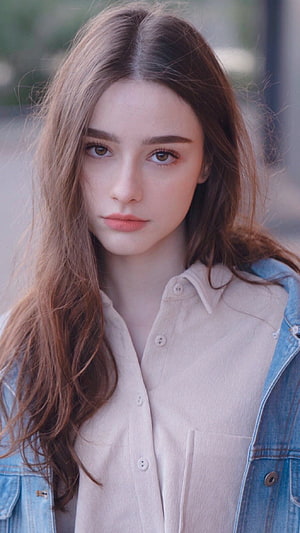 Portrait of a young woman with long brown hair wearing a beige shirt and denim jacket, Dasha Taran HD phone wallpaper