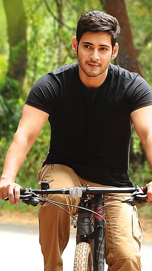 Mahesh Babu Riding a Mountain Bike Through a Lush Green Forest Path HD phone wallpaper