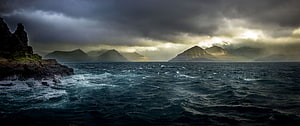 Dramatic Stormy Seascape with Dark Clouds and Distant Mountains HD wallpaper