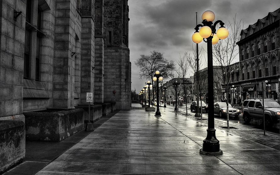 Moody Black and White City Street with Glowing Yellow Street Lamps on Wet Pavement HD wallpaper