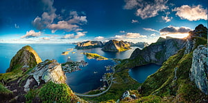 Stunning panoramic view of Reine village in the Lofoten Islands, Norway, featuring dramatic mountains, a serene fjord, and a vibrant sunset sky HD wallpaper
