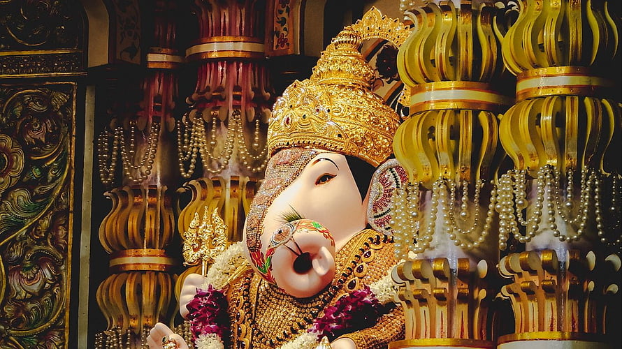 Ornate Ganesha Statue Adorned with Gold Crown and Pearls in Temple HD wallpaper