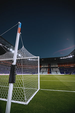 Empty football stadium at night with goal net in the foreground and illuminated stands HD phone wallpaper
