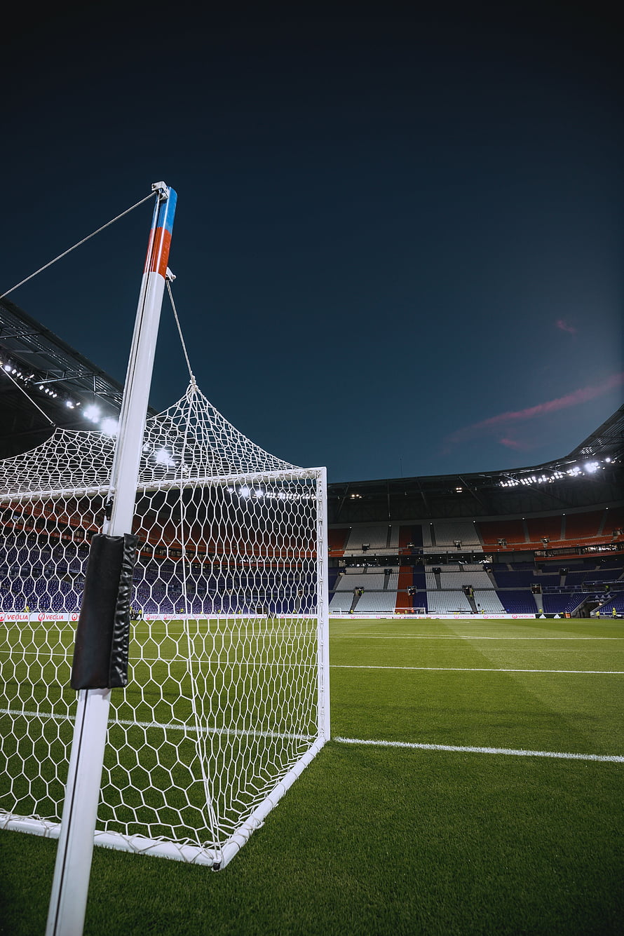 Empty football stadium at night with goal net in the foreground and illuminated stands HD phone wallpaper