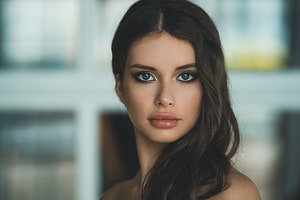 Close-up portrait of a woman with dark wavy hair and striking blue eyes against a soft blurred background, Unknown Model, gorgeous, model, beautiful, woman HD wallpaper