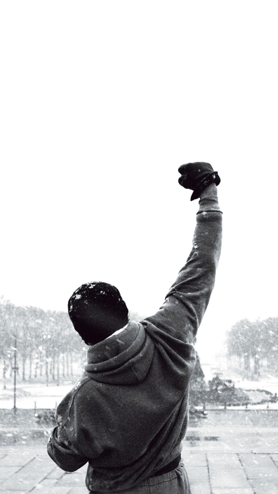 Rocky Balboa raising a gloved fist in a snowy urban plaza HD phone wallpaper