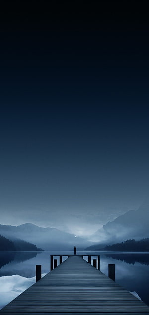 Solitary Figure Standing on Wooden Pier Over Misty Lake at Dusk HD phone wallpaper