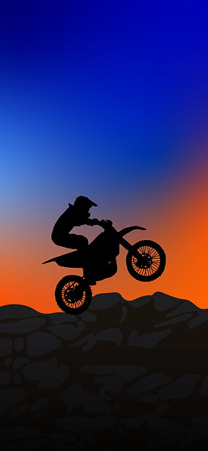 Motocross Rider Silhouette Performing a Wheelie Against a Vibrant Sunset Sky HD phone wallpaper