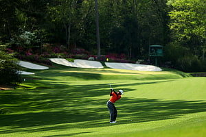 Golf Swing on Lush Green Fairway with Sand Bunkers and Wooded Background HD wallpaper