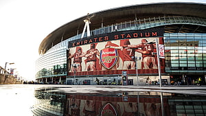 Emirates Stadium Exterior with Arsenal Crest and Player Mural on Glass Facade HD wallpaper
