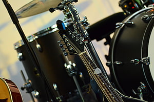 Close-up of an electric guitar headstock set against a black drum kit on stage HD wallpaper