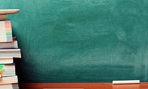 Classroom Chalkboard with Stacked Books and Chalk on Wooden Desk HD wallpaper