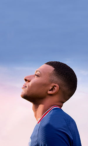 Kylian Mbappe Profile Portrait in PSG Jersey Against a Soft Blue Sky HD phone wallpaper