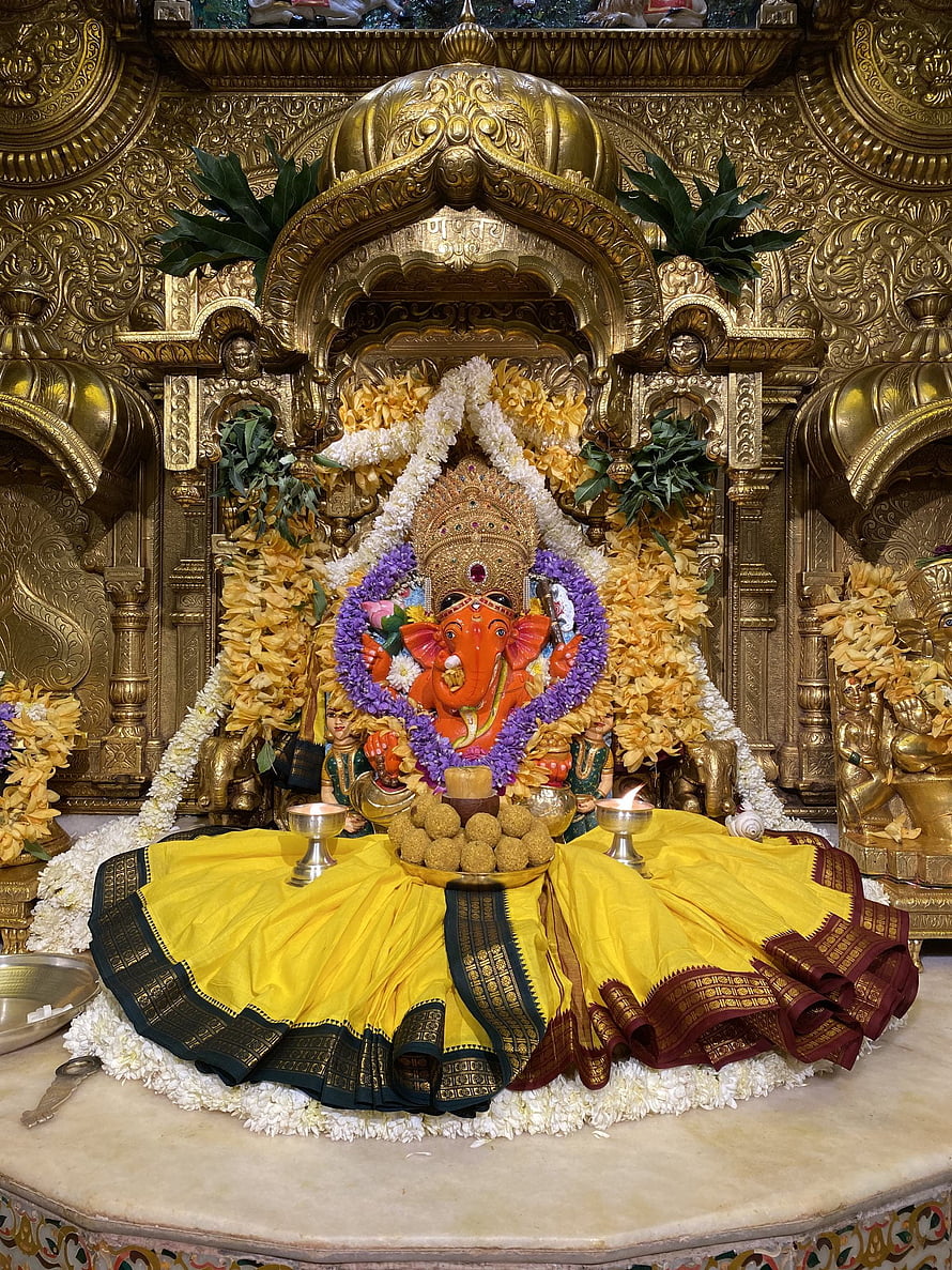 Lord Ganesha Murti in Golden Temple with Flower Garlands and Yellow Silk HD phone wallpaper