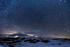 Starry Night Sky Over Snow-Capped Mountain Range in Winter Landscape HD wallpaper