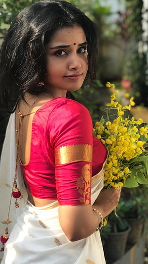Woman in traditional white saree with red blouse holding yellow flowers, Anupama Parameswaran, South Heroine HD phone wallpaper