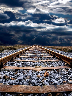 Dramatic Storm Clouds Over a Straight Railway Track Stretching to the Horizon HD phone wallpaper