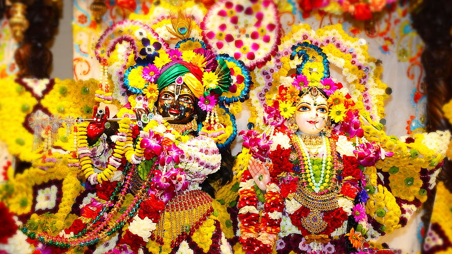 Floral Krishna and Radha Deities Adorned in Vibrant Marigold Garlands and Jewels HD wallpaper