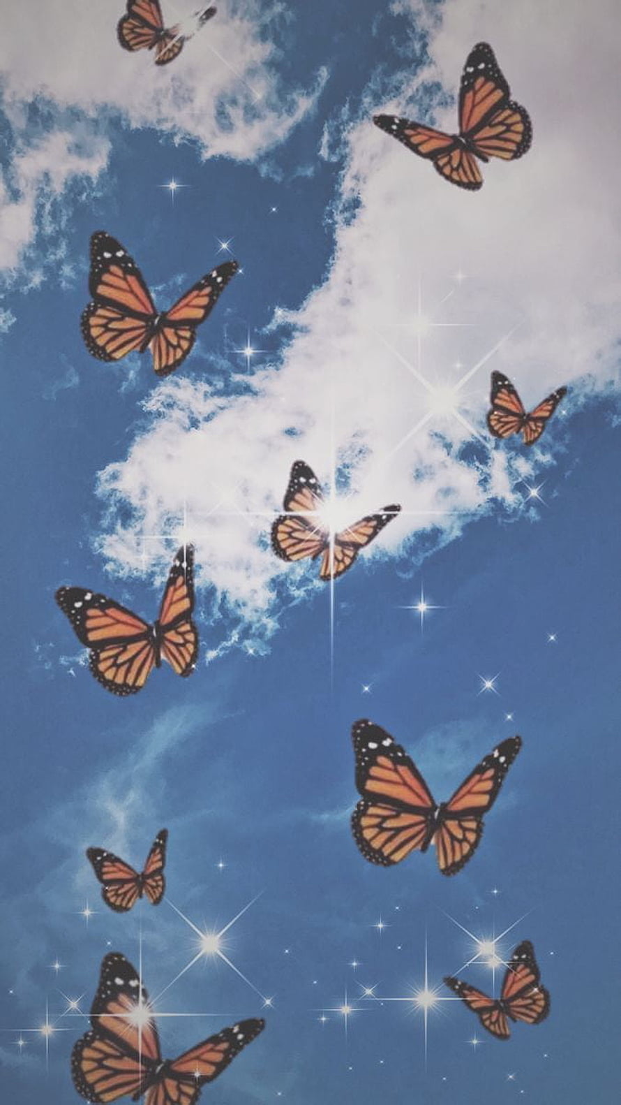 Monarch butterflies soaring through a blue sky with soft clouds and sparkling light effects HD phone wallpaper